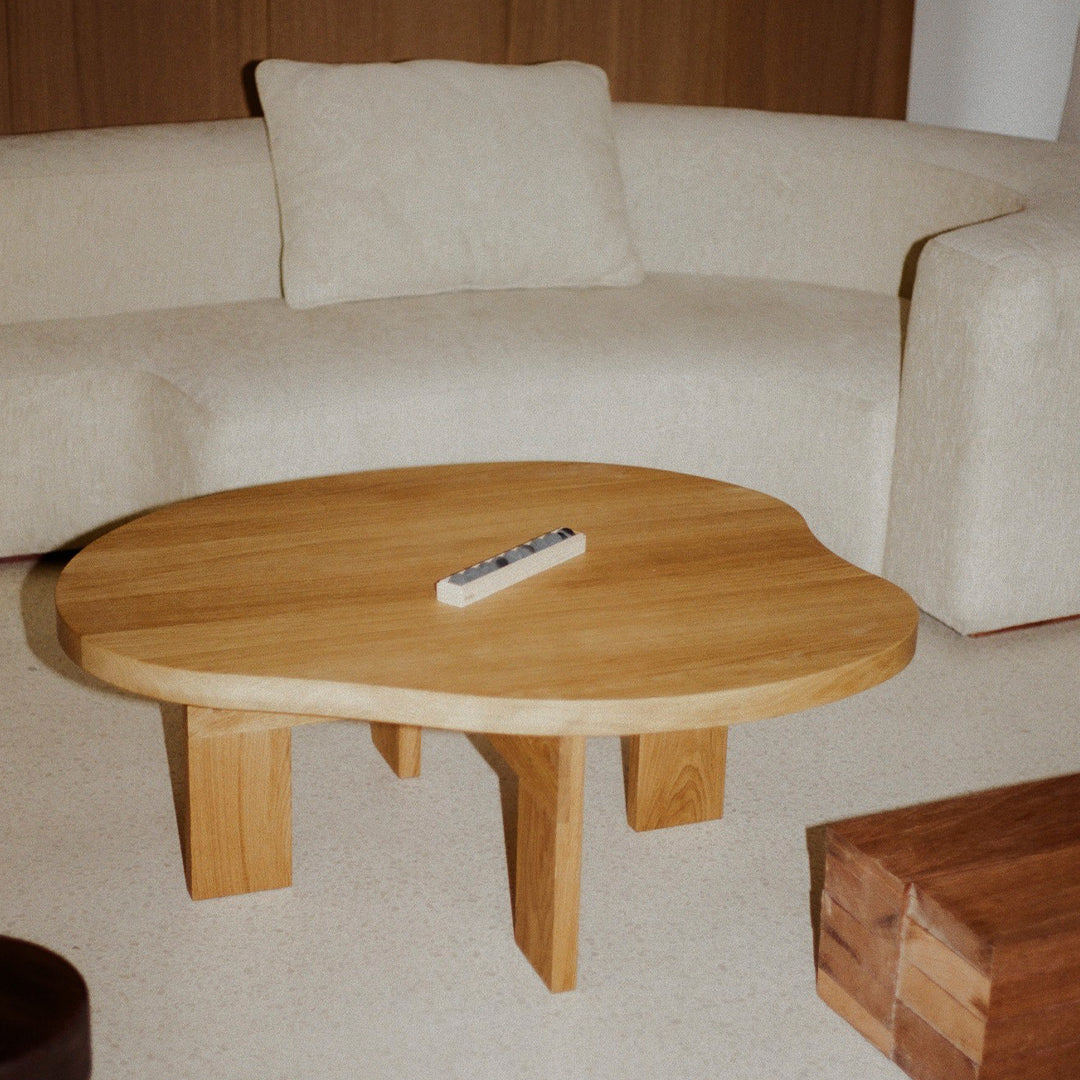 Natural wood coffee table with a unique organic shape, featuring a light honey hue and smooth, simple design.