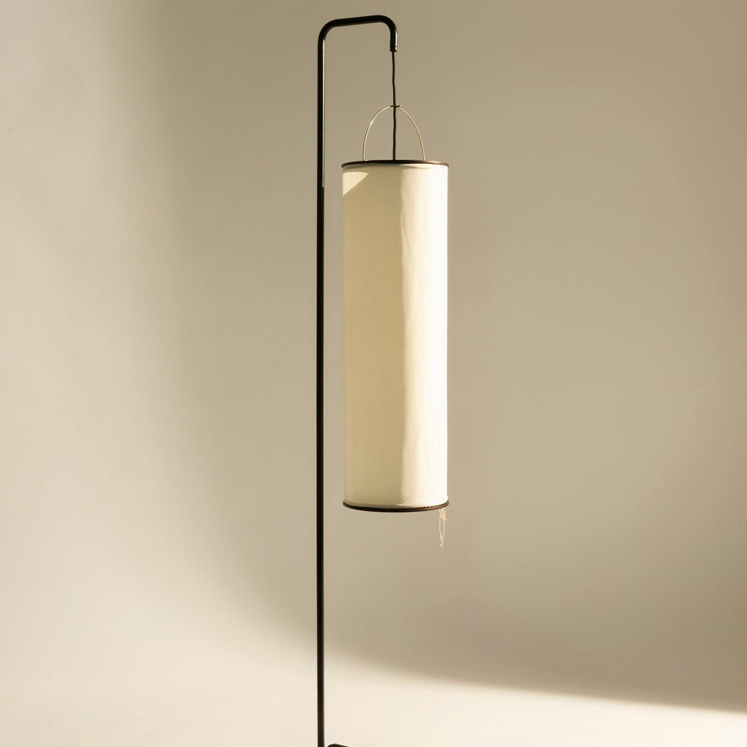 Sleek black metal lamp stand with a modern white cylindrical shade, creating a minimalist aesthetic.