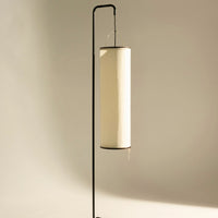 Sleek black metal lamp stand with a modern white cylindrical shade, creating a minimalist aesthetic.