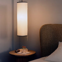 Modern pendant lamp with a sleek white shade, accented by a black rim, against a soft gray wall. Warm, inviting atmosphere.