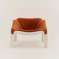 Rust-colored velvet armchair with smooth white legs, featuring modern ergonomic design and minimalistic style.