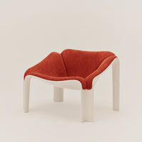 Red and white modern chair with a unique curved design and textured upholstery in a contemporary setting.