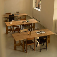 Light wood tables with natural finishes and contrasting dark wooden chairs in a minimalist, cozy workspace setting.