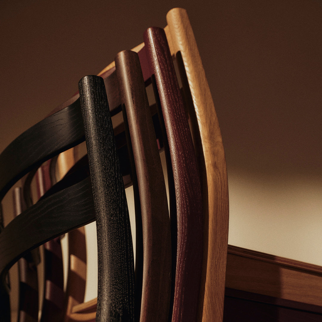 Elegant wooden dining chairs in black, dark brown, and natural wood tones with a sleek, minimalist design.