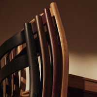 Elegant wooden dining chairs in black, dark brown, and natural wood tones with a sleek, minimalist design.