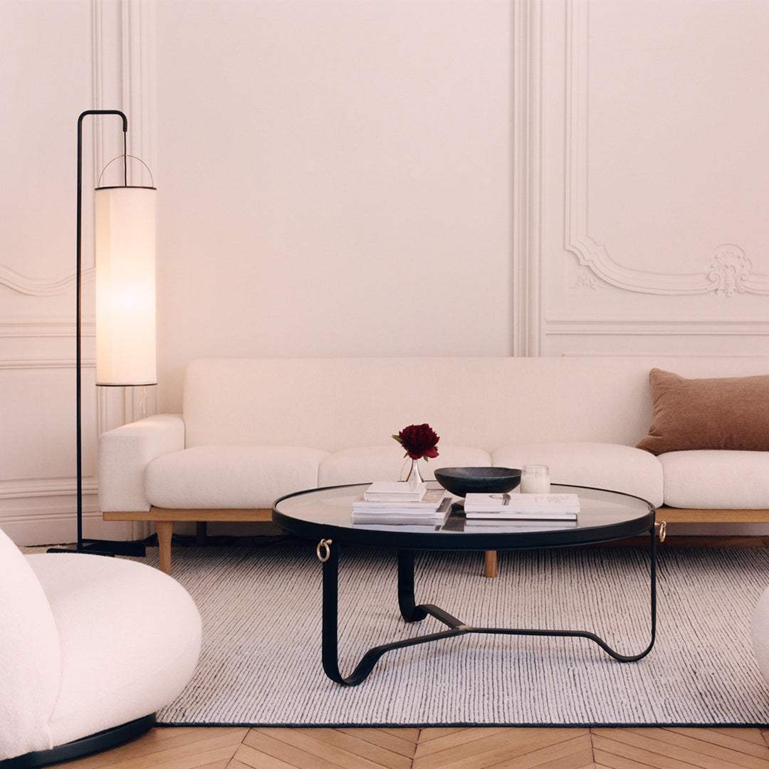 Modern living room featuring a white sofa, beige pillow, and black round coffee table on a light textured rug.