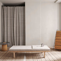 Grey textured curtain, light wooden furniture, neutral-toned space, minimalist design with soft, muted colors.
