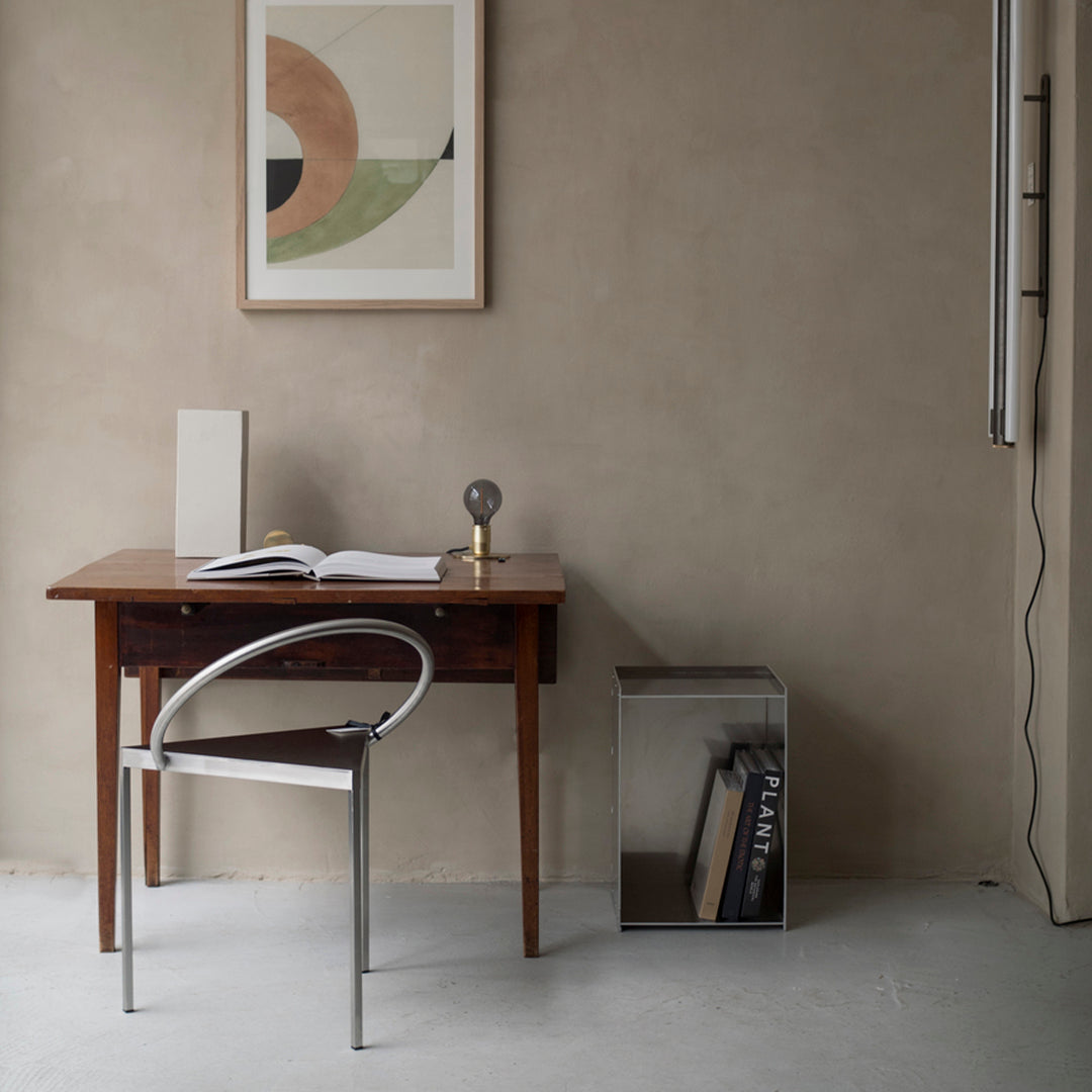 Minimalist workspace featuring earth tones, geometric patterns in wall art, and a clear acrylic chair.