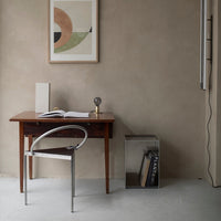 Minimalist workspace featuring earth tones, geometric patterns in wall art, and a clear acrylic chair.