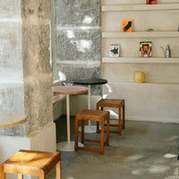 Stylish stools in natural wood tones and a sleek black finish, set against a textured concrete background.