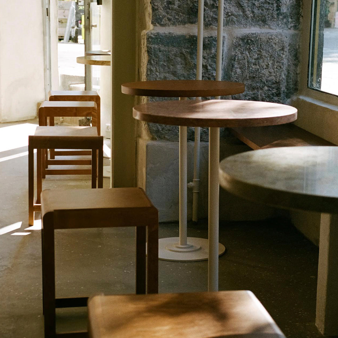 Modern wooden tables with warm tones and smooth finishes in a bright, minimalistic café setting.