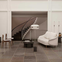 Elegant white sofa and minimalistic chairs on a slate gray floor, accented by smooth black and white patterns.