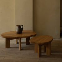 Natural wood coffee tables in warm, honey tones with smooth, oval shapes; minimalist design on a light wooden floor.