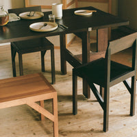 Modern dining set featuring a natural wood table and black chairs, complemented by a light wood floor.