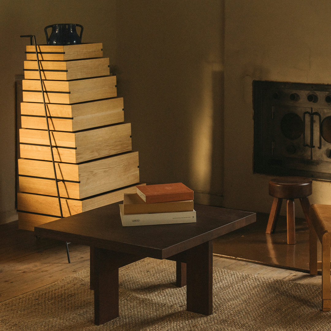 "Modern wooden coffee table in a warm, neutral-toned room, with stacked light and dark books on top."