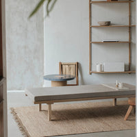 Modern light gray coffee table on natural fiber rug, accented by earthy tones and sleek wooden shelves.