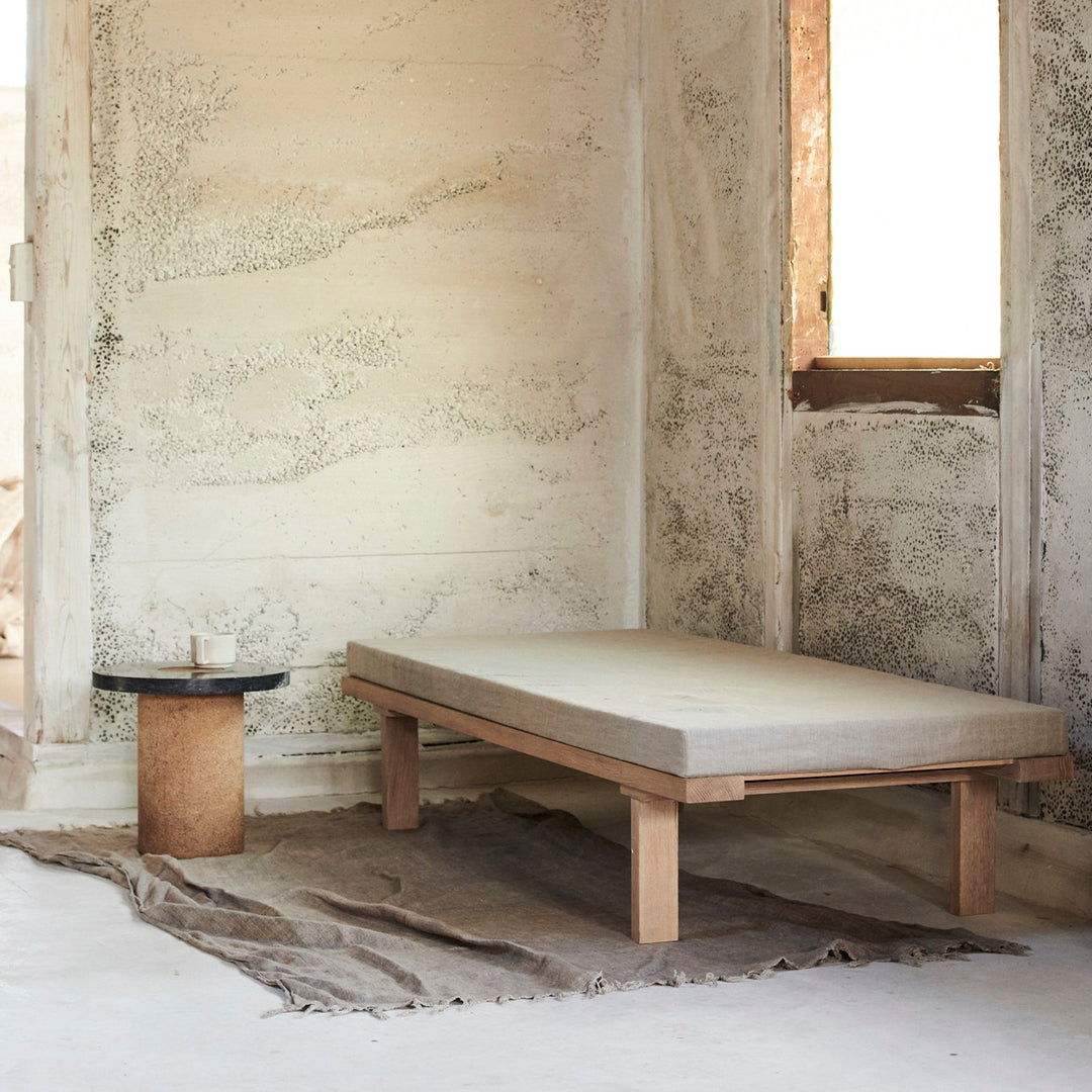 Neutral beige mattress on wooden bed frame, complemented by earthy tones in the surroundings and subtle textured walls.