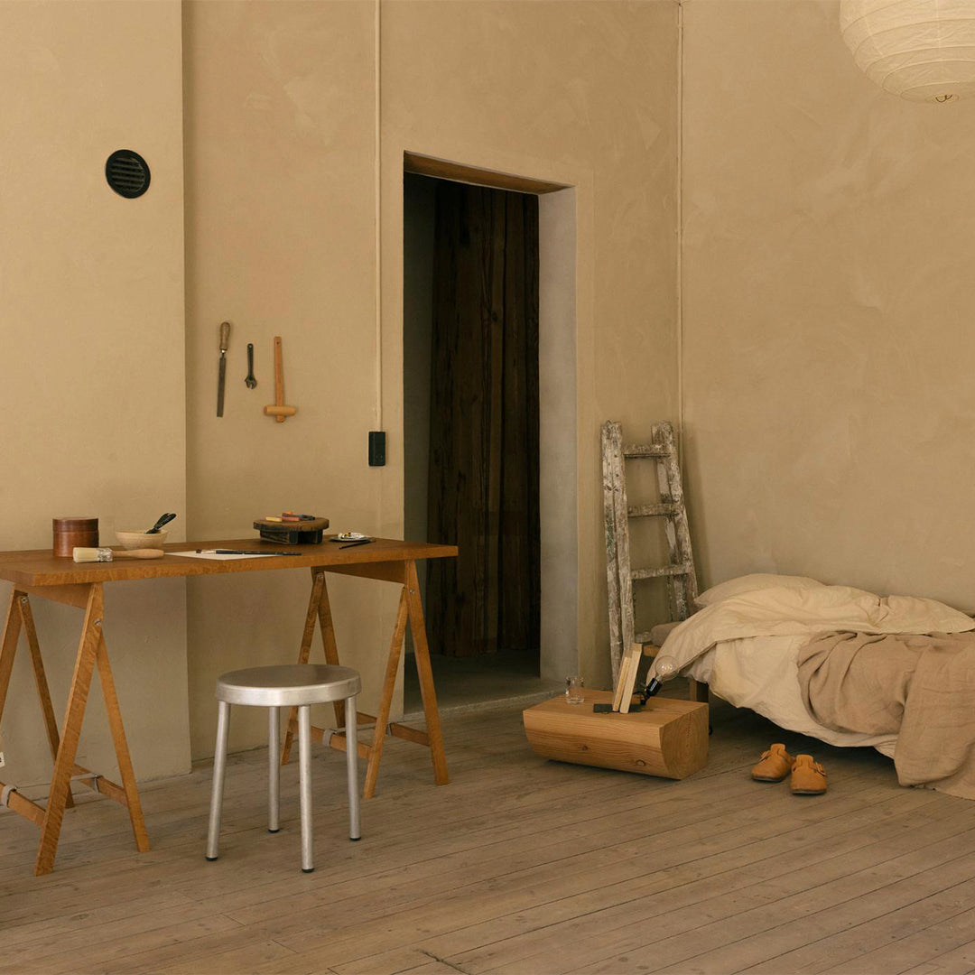 Warm beige walls, soft beige bedding, wooden tones, and subtle earth tones create a cozy, minimalist room ambiance.