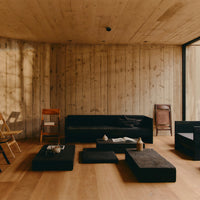 Black furniture with textured surfaces against a natural wood floor and concrete walls, creating a modern, minimalist aesthetic.