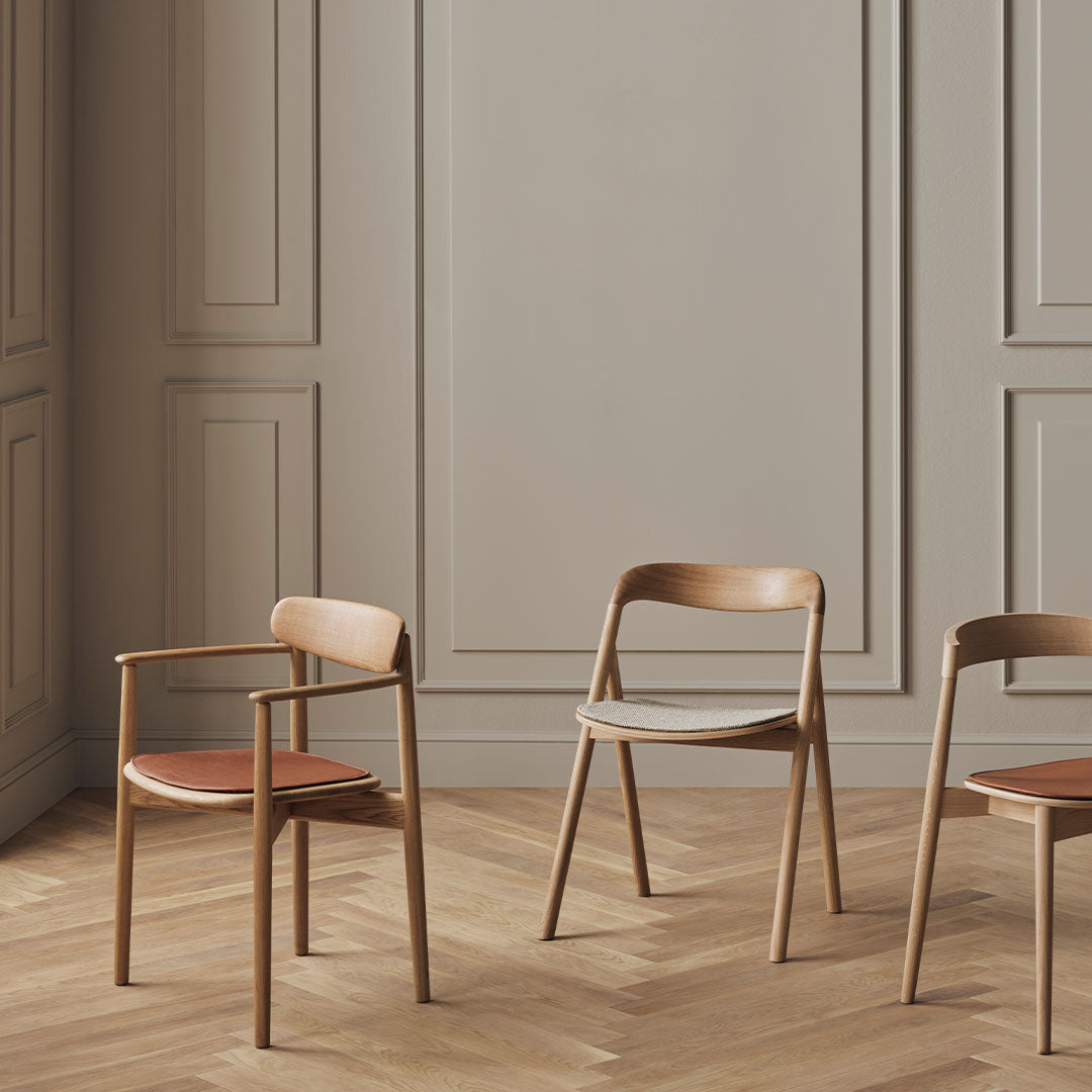 "Modern wooden chairs in light brown, featuring soft gray and warm orange cushion accents, set against a neutral backdrop."