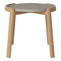 Light wooden legs support a round gray concrete tabletop with a smooth finish, showcasing minimalist design.