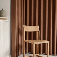 Brown textured curtains paired with a light wooden chair, showcasing a warm, cozy aesthetic. Perfect for any modern decor.