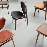 Colorful assortment of chairs in black, brown, and tan on a neutral gray background with smooth, modern design.