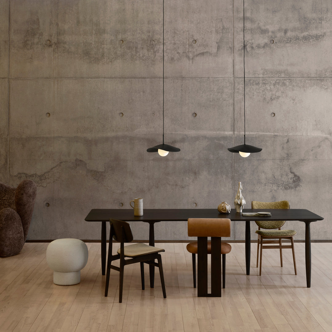 Modern dining room featuring neutral tones, black accents, and earthy patterns on furniture against a concrete backdrop.