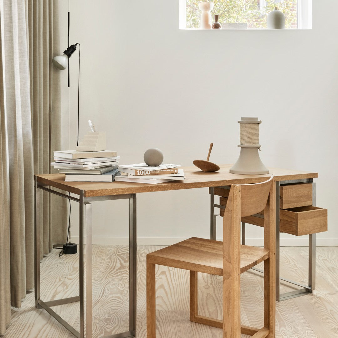 Light wood desk with metal accents, paired with a minimalistic wooden chair, set against soft neutral tones.