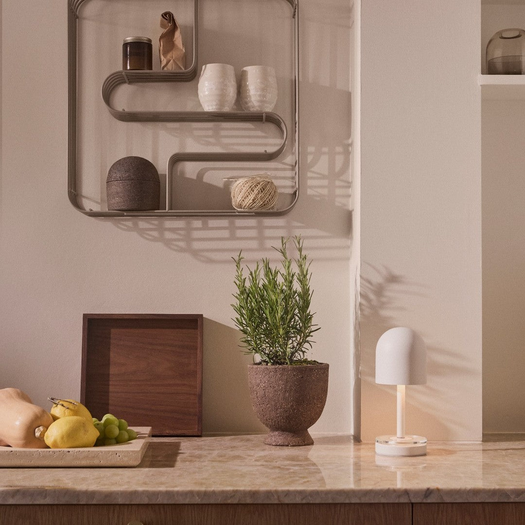 "Neutral tones with earthy textures, featuring a light gray marble surface, cream accents, and green plant highlights."