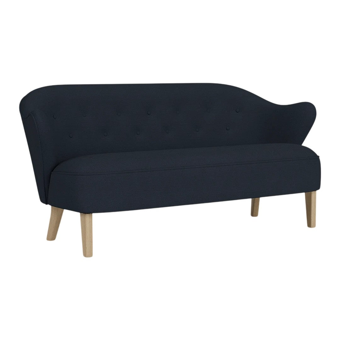Elegant navy blue sofa with a curved silhouette and tufted detailing, complemented by light wooden legs.