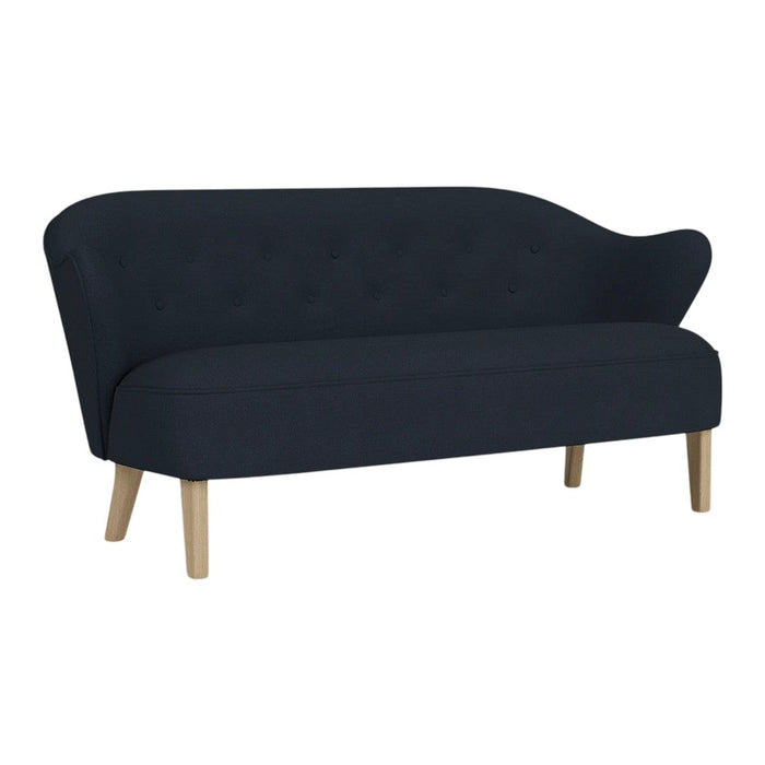 Elegant navy blue sofa with a curved silhouette and tufted detailing, complemented by light wooden legs.