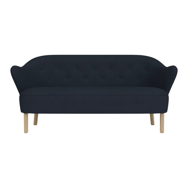 Navy blue tufted sofa with curved backrest and light wooden legs. Elegant, minimalist design for modern interiors.