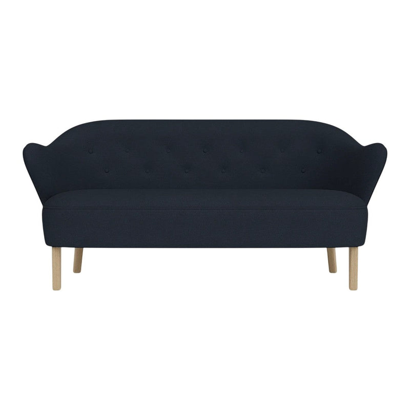 Navy blue tufted sofa with curved backrest and light wooden legs. Elegant, minimalist design for modern interiors.