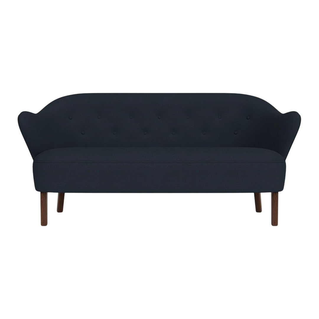 Deep navy blue tufted sofa with smooth upholstery and elegant curved arms, featuring wooden legs. Perfect for modern decor.