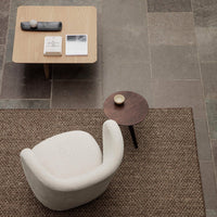 Cozy cream chair on textured brown rug, paired with a wooden coffee table and minimalist decor in neutral tones.