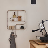 Stylish silver wire shelf with geometric design, featuring natural wood and textured black accents against a neutral wall.