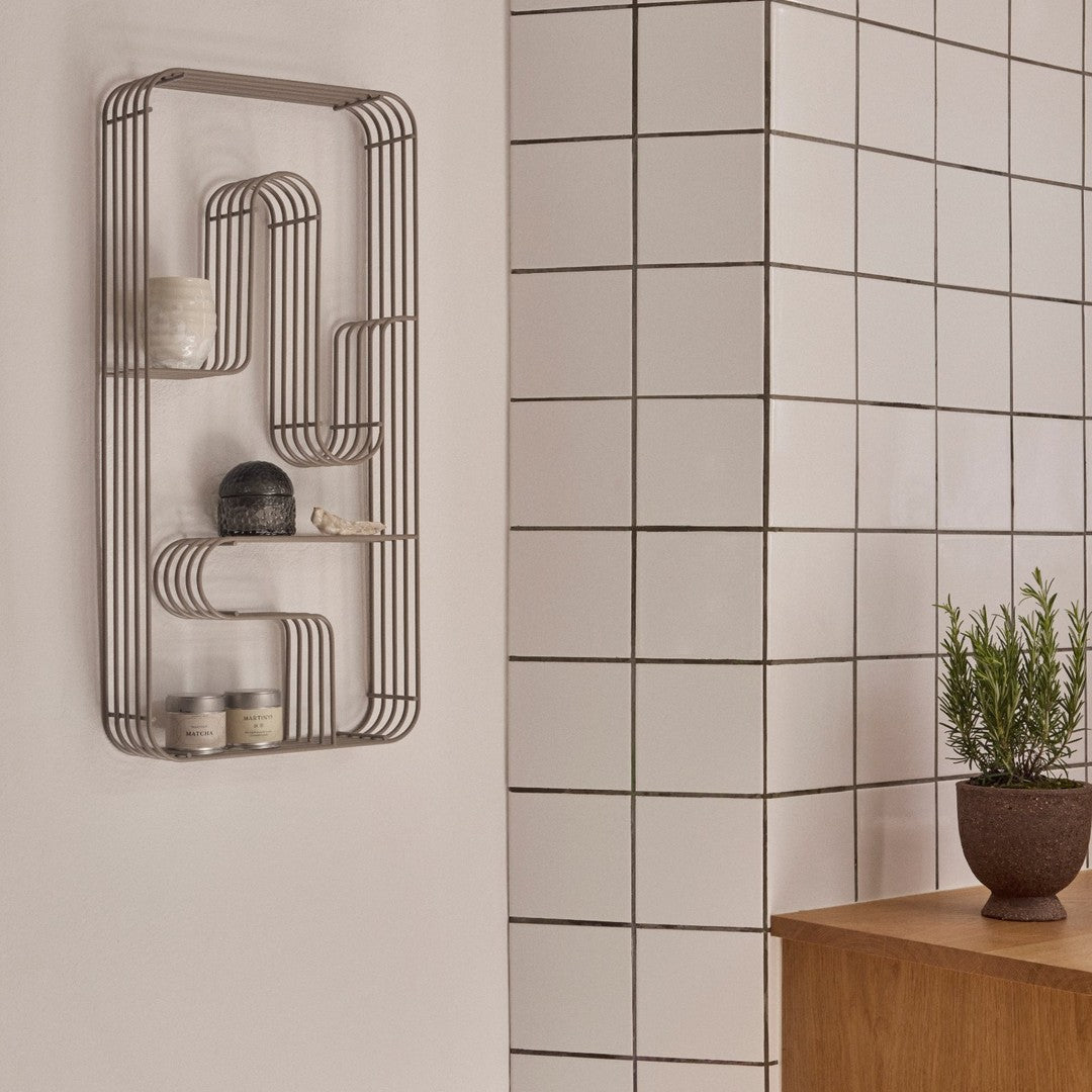 Modern minimalist shelf in warm taupe against a textured white tiled wall, showcasing soft tones and clean lines.