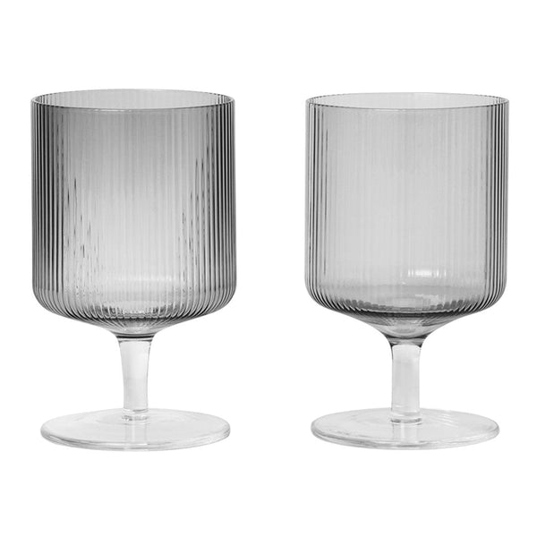 Set of two gray glass goblets featuring vertical ribbed patterns and clear stems. Elegant and modern drinkware.