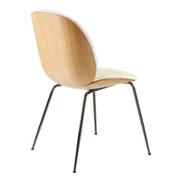 Light wood chair with a textured cream seat and black metal legs, featuring a minimalist design.