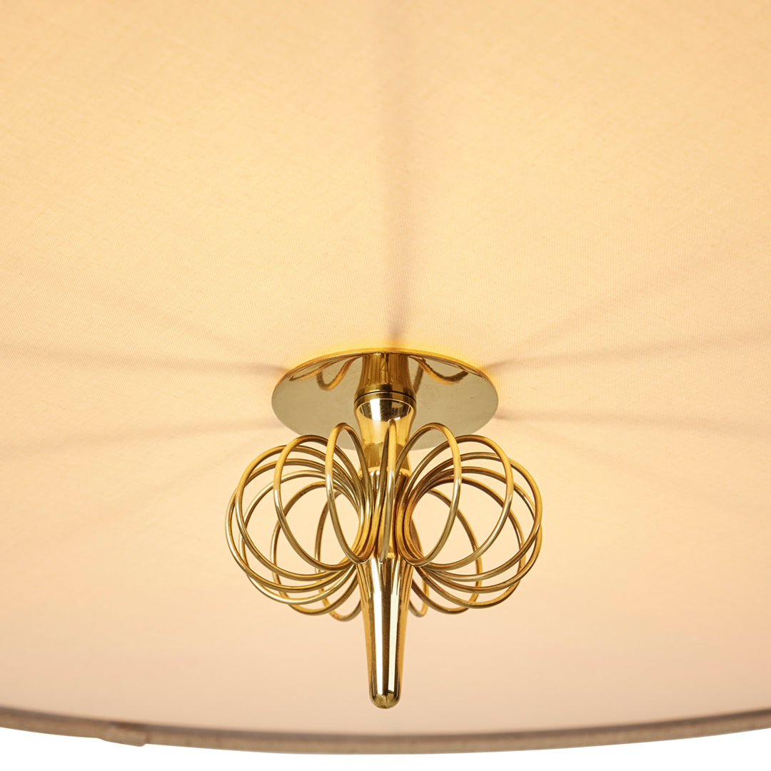 Gold chandelier with intricate circular patterns against a soft beige shade, creating an elegant ambiance.