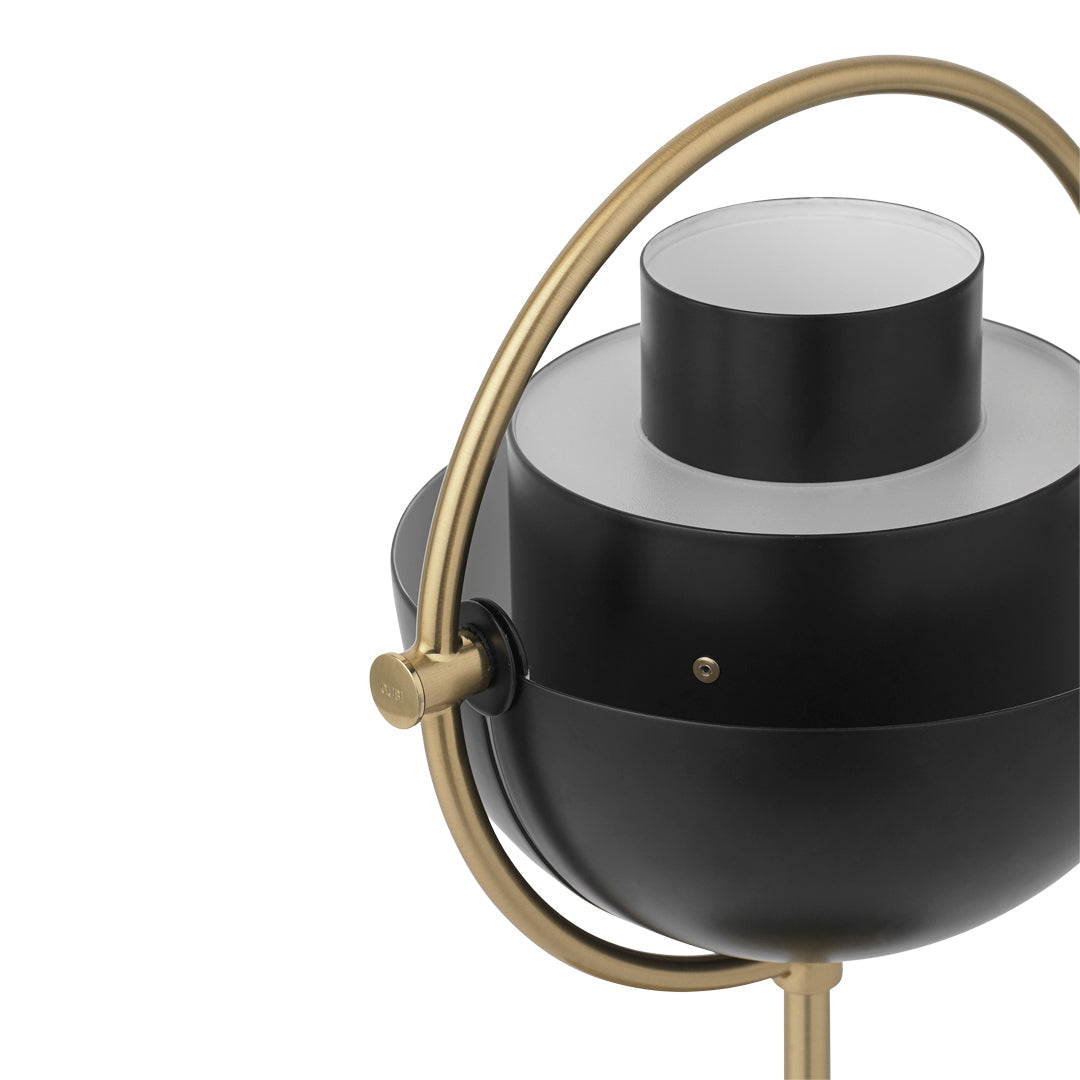 Black and gold modern lamp with a round base and sleek cylindrical shade, perfect for contemporary decor.