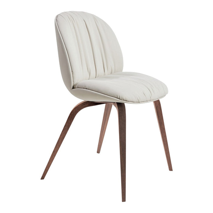 Cream tufted chair with rich walnut legs, blending soft neutrals with earthy tones for a modern look.