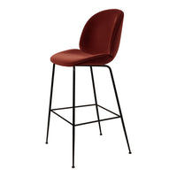 Rust red upholstered bar stool with a sleek black metal frame and minimalist design. Perfect for modern spaces.