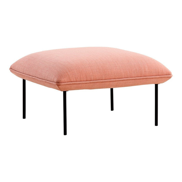 Soft coral pink upholstered ottoman with a smooth texture and black metal legs. Perfect for modern decor.