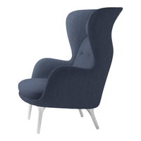 Navy blue upholstered armchair with elegant curves and subtle button accents, set on sleek white legs.