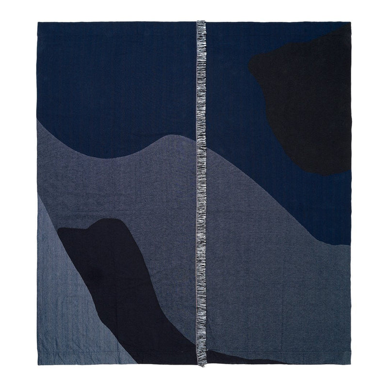 Abstract patchwork blanket in shades of navy blue, dark gray, and charcoal, featuring fluid, wavy patterns.