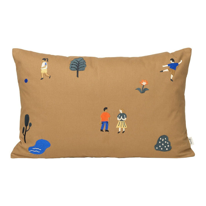 Brown decorative pillow featuring playful patterns of trees, people, and flowers in blue and orange hues.