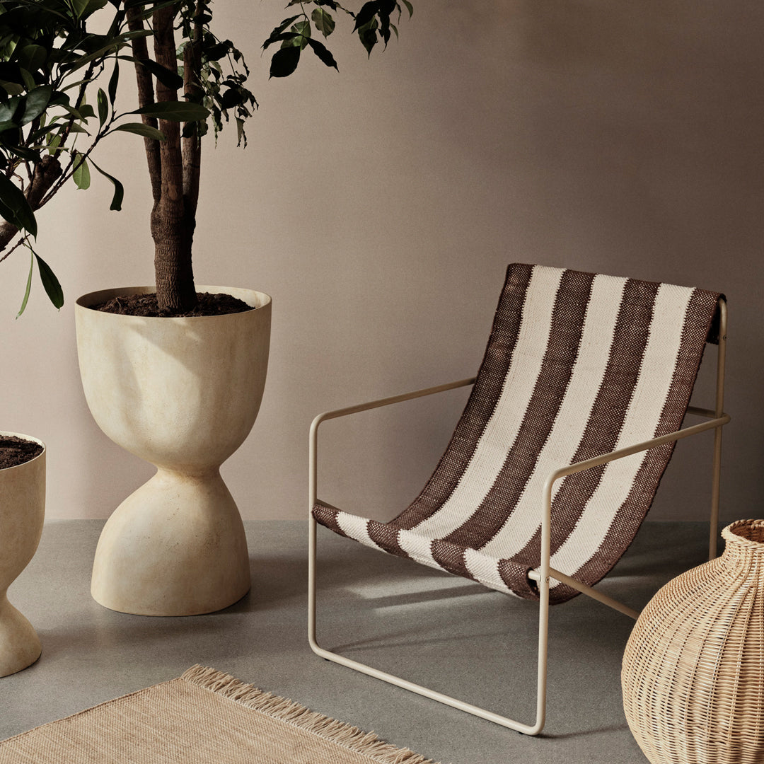 Stylish brown and cream striped chair with a sleek metal frame, complemented by neutral decorative elements.