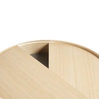 Light oak round table with a smooth natural wood grain and minimalist design, featuring a contrasting dark triangular section.